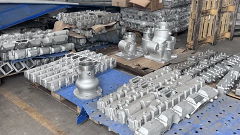 A variety of metal components organized on pallets in a workshop